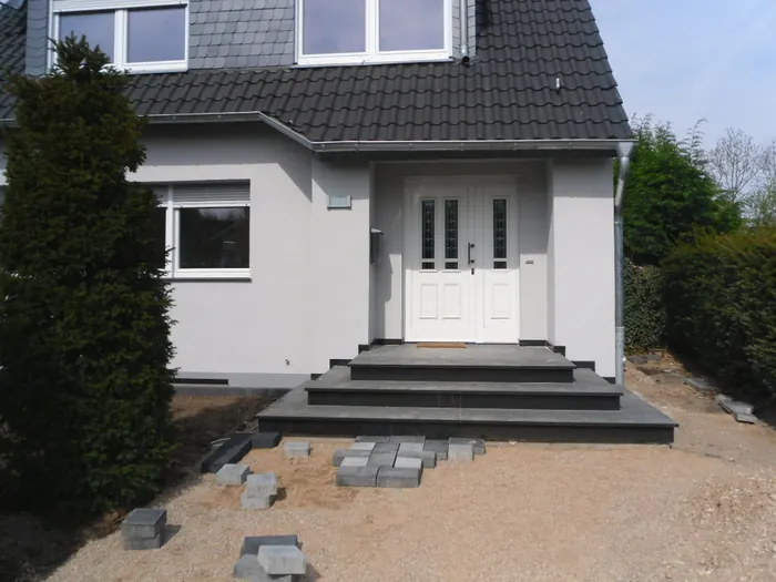 Fertig verputzte helle Hausfassade mit Eingangstreppe aus Naturstein