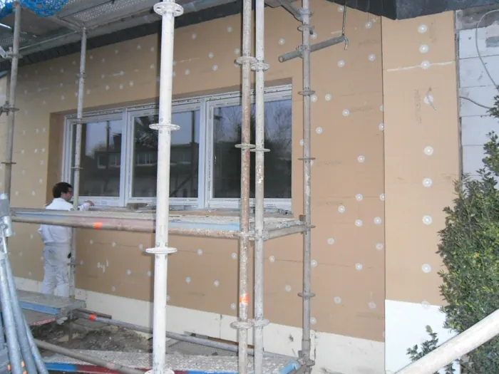 Hauswand mit angesetzten Dämmplatten und Tellerdübeln, Haus im Gerüst