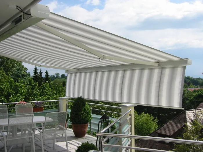 Ausgefahrene Gelenkarmmarkise mit Volant über einer Dachterrasse mit Sitzgruppe