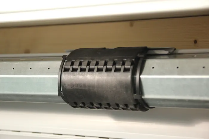 Blick in einen geöffneten Rollladenkasten auf die Rollladenwelle mit aufgesetzter Kupplung