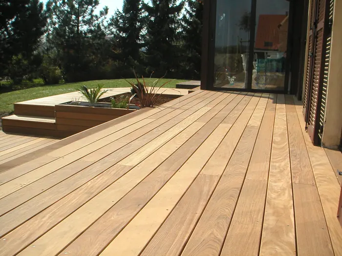 Hartholzterrasse mit Sitzstufen und angrenzendem Pflanzbeet vor einer Terrassentür