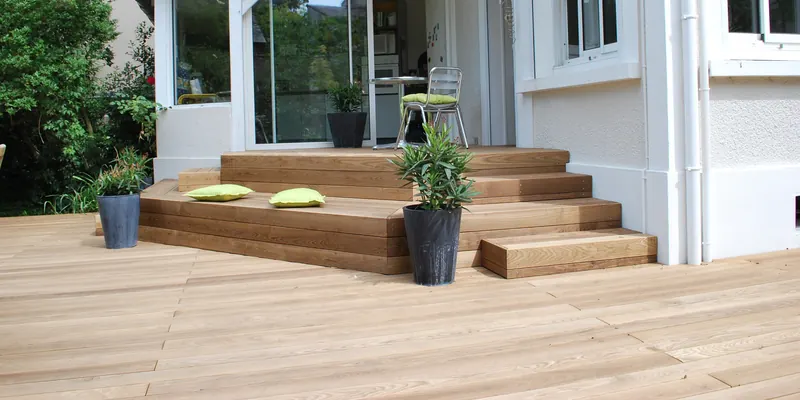 Holzterrasse mit breiten Stufen, die zu einer Terrassentür hinaufführen